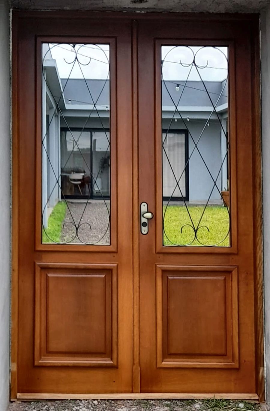 Porta dupla de madeira com vidro e grade de ferro